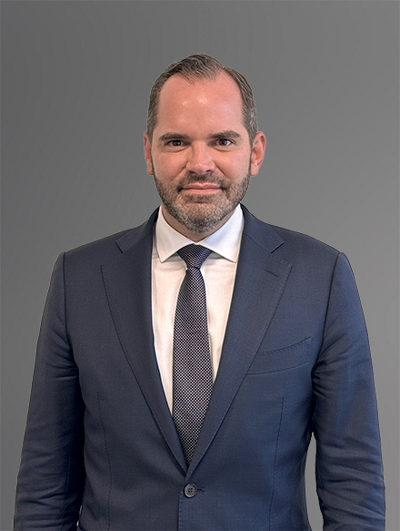 El abogado Frank R. Pumarejo-Martin con traje azul marino, camisa blanca y corbata gris
